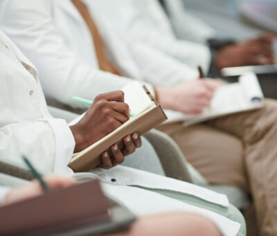 Group of Medical Students Taking Notes in Lecture Multi ethnic group of young people wearing lab coats while sitting in row in audience and taking notes in lecture on medicine, copy space